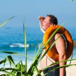 orange safety ring on man shoulder near body of water