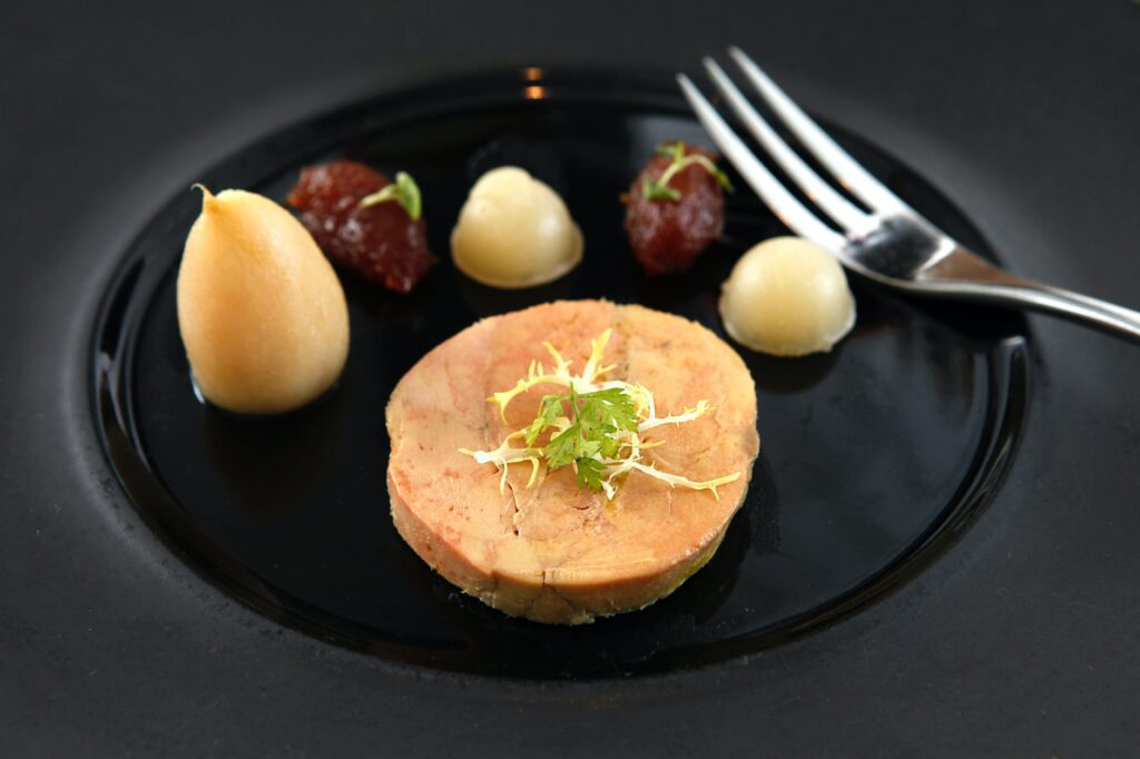 a foie gras with stainless fork on a ceramic plate