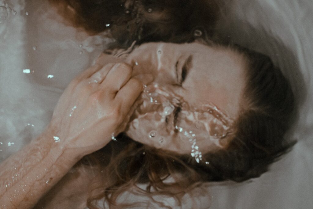 depressed woman under water in tub