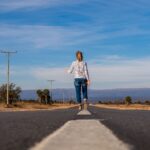 back view of a woman walking in the middle of the road
