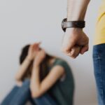 man clenching fist near a woman covering face while sitting