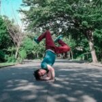 man doing head stand on road