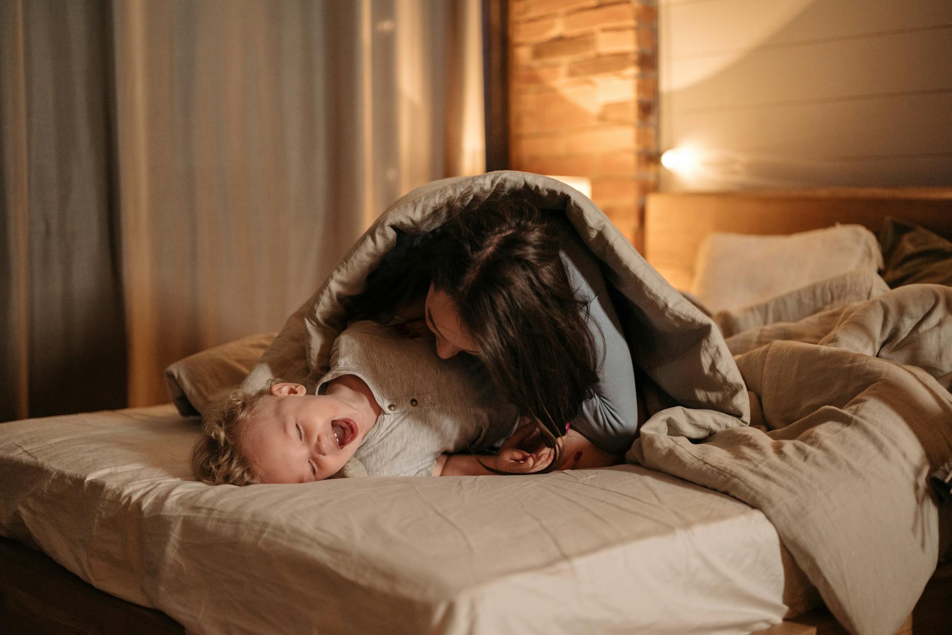 mother and child playing on bed