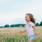 smiling girl running towards left on green field